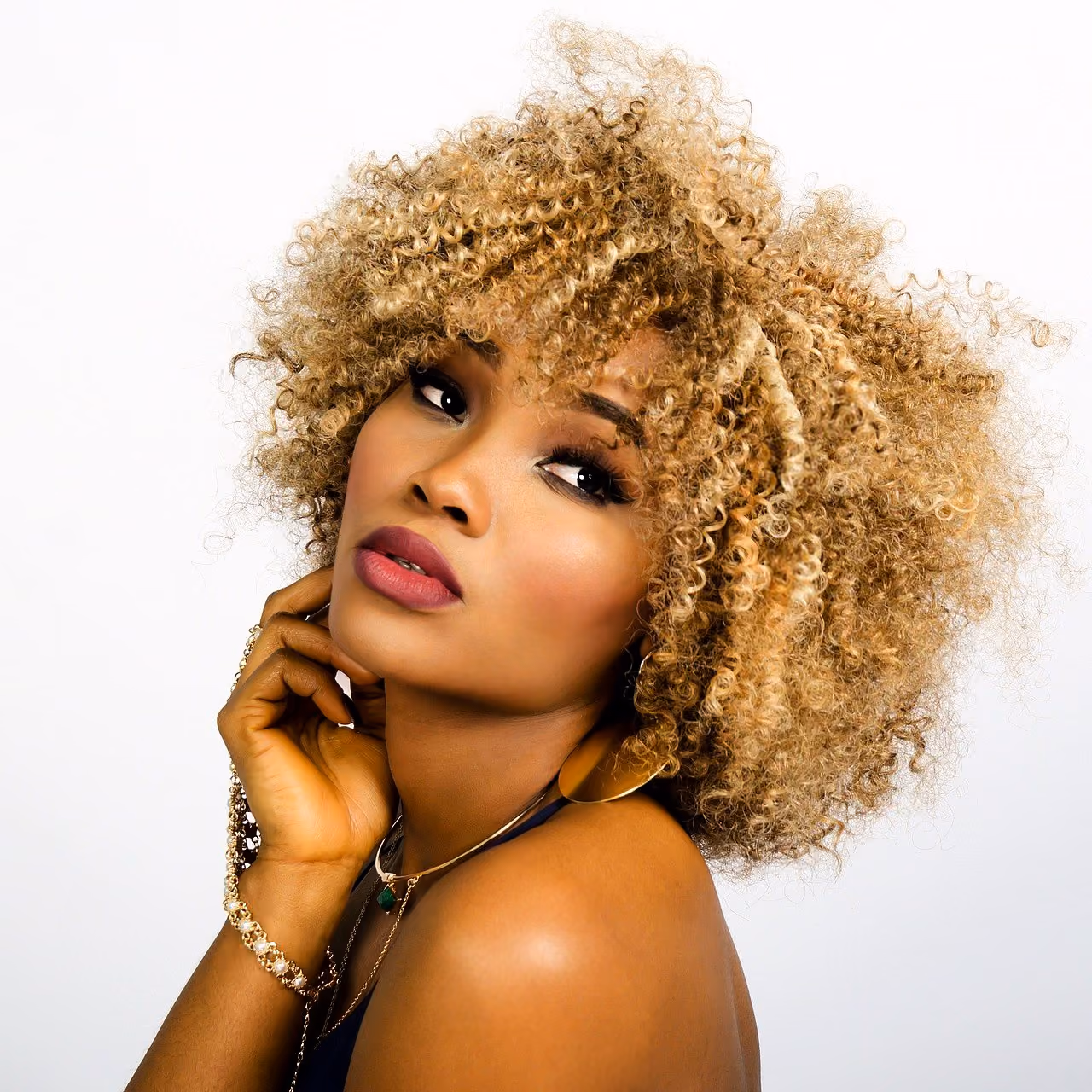 After: Woman with golden curly hair and glossy lips resting her chin on her hand
