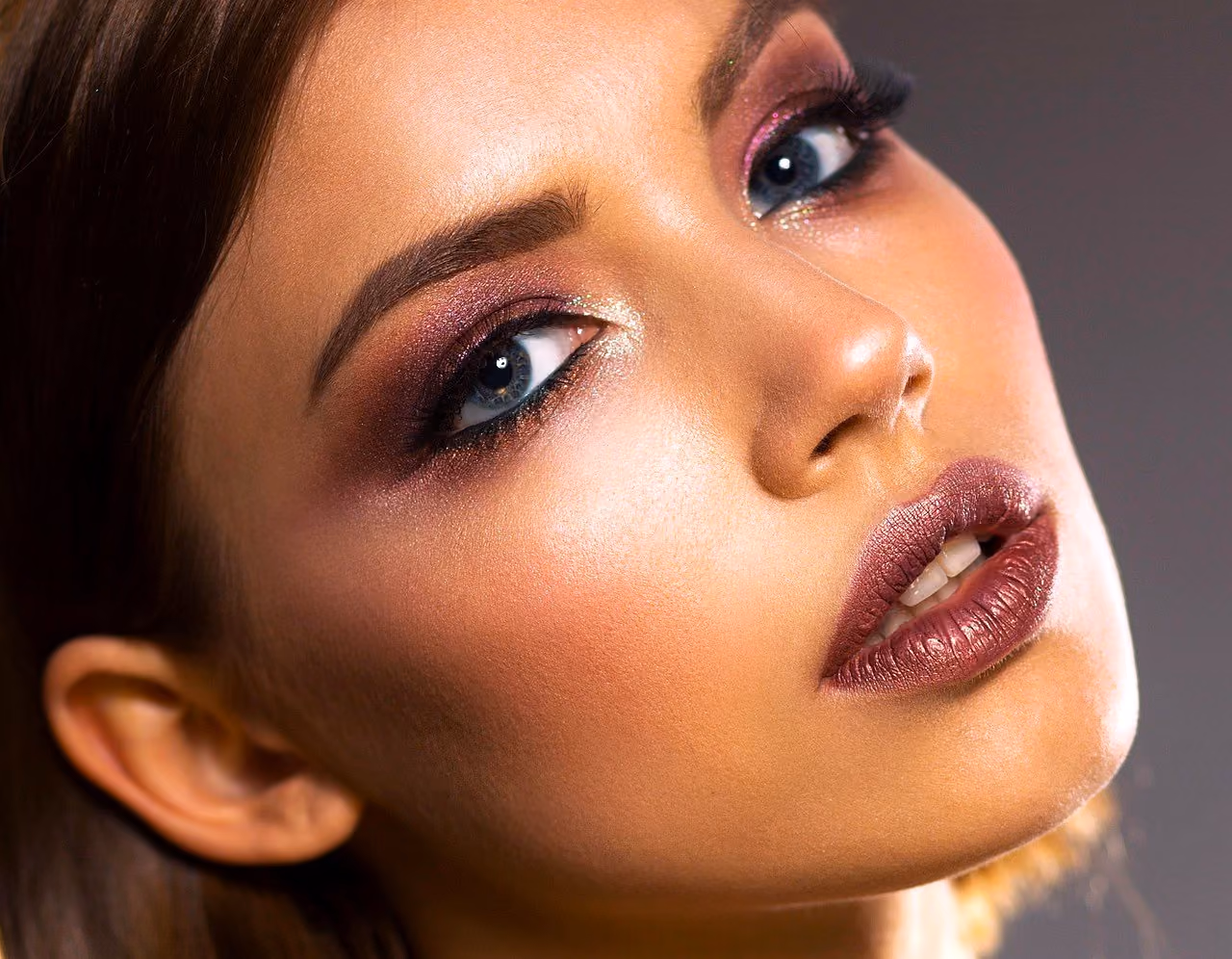 After: Close portrait of a woman with smoky eye makeup looking upward