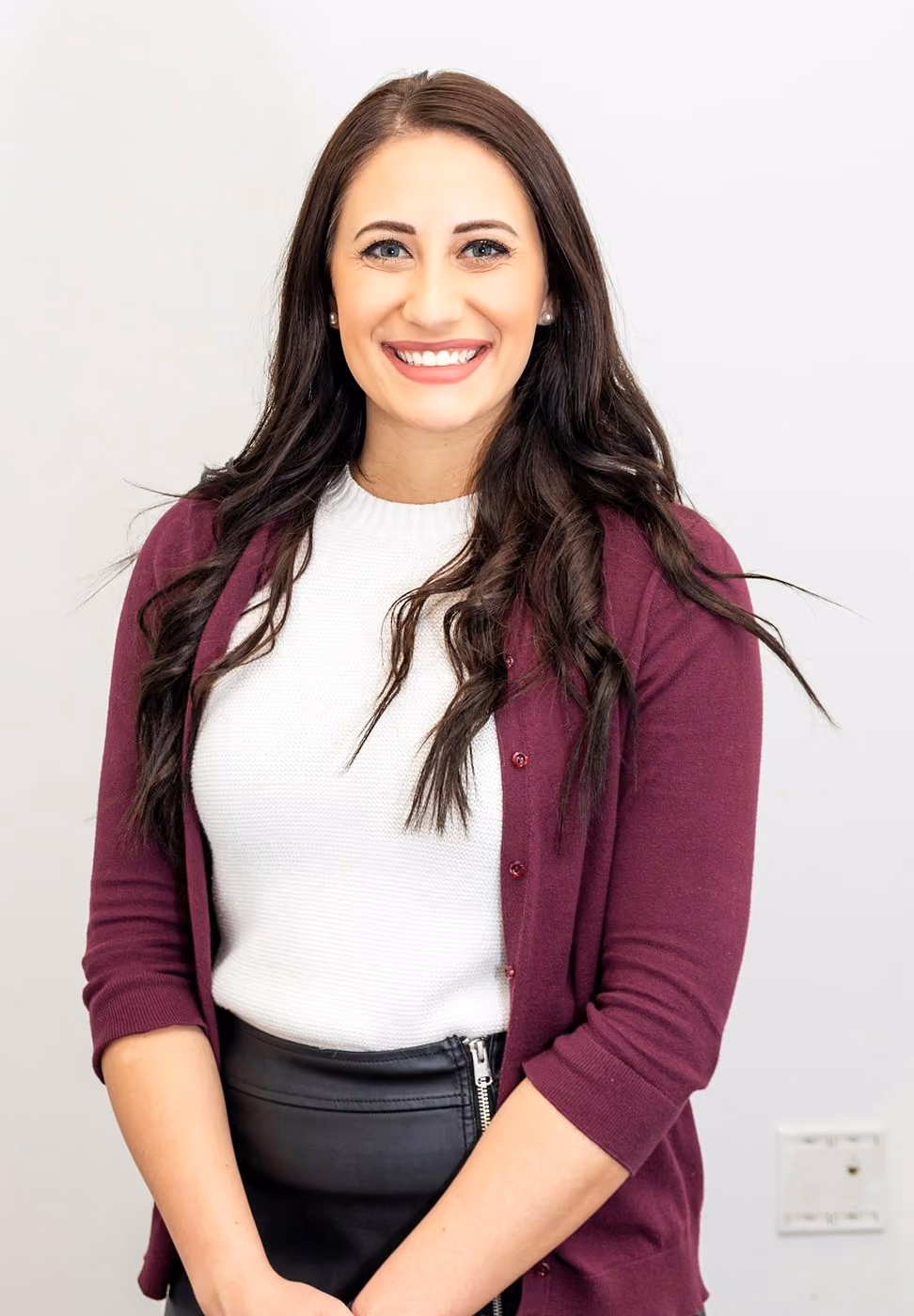 After: Woman with long dark hair and a burgundy cardigan smiling, light backdrop