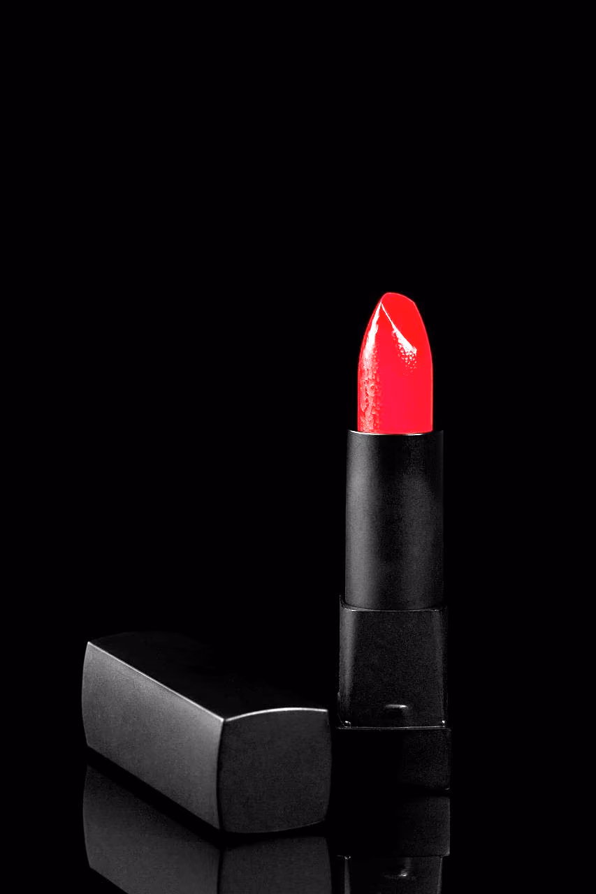 After: Red lipstick and its black case photographed on a dark glossy surface
