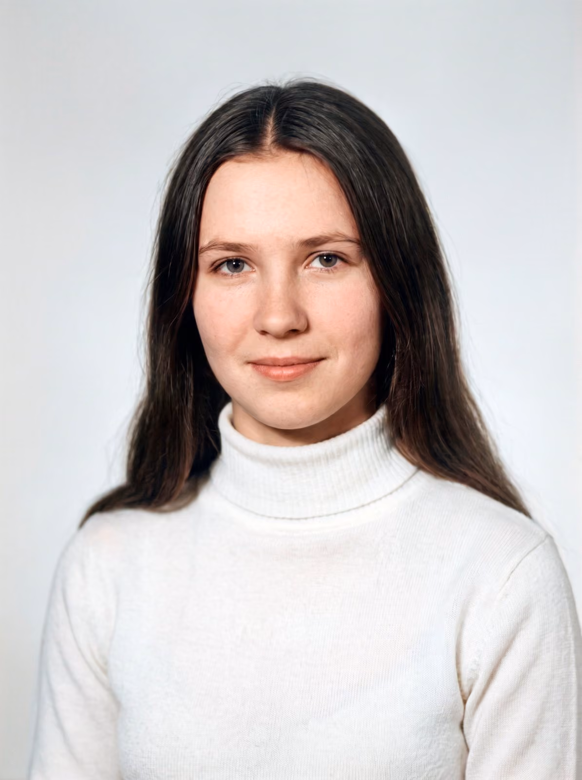 After: Studio portrait of a young woman with long dark hair in a white turtleneck, restored from a torn and stained print