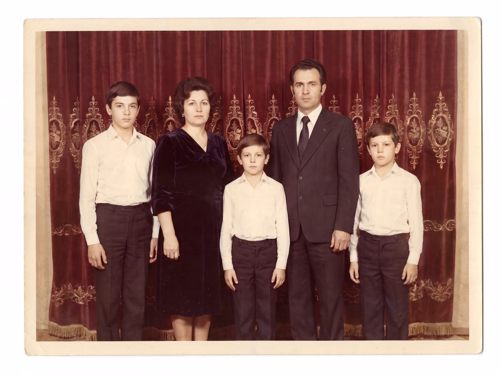 After: Parents and three boys posed in front of a red patterned curtain, restored from a creased and stained print