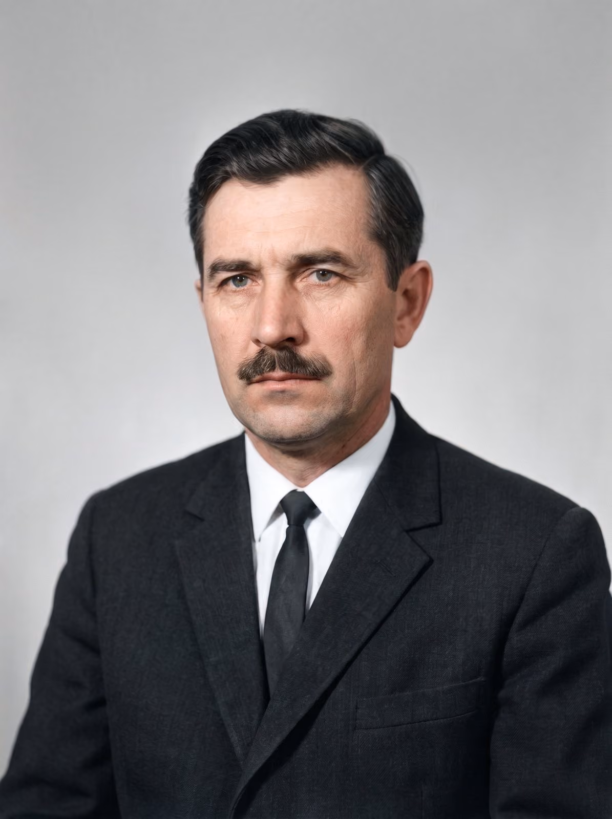 After: Formal portrait of a man with a moustache in a dark suit and tie, restored from a cracked print