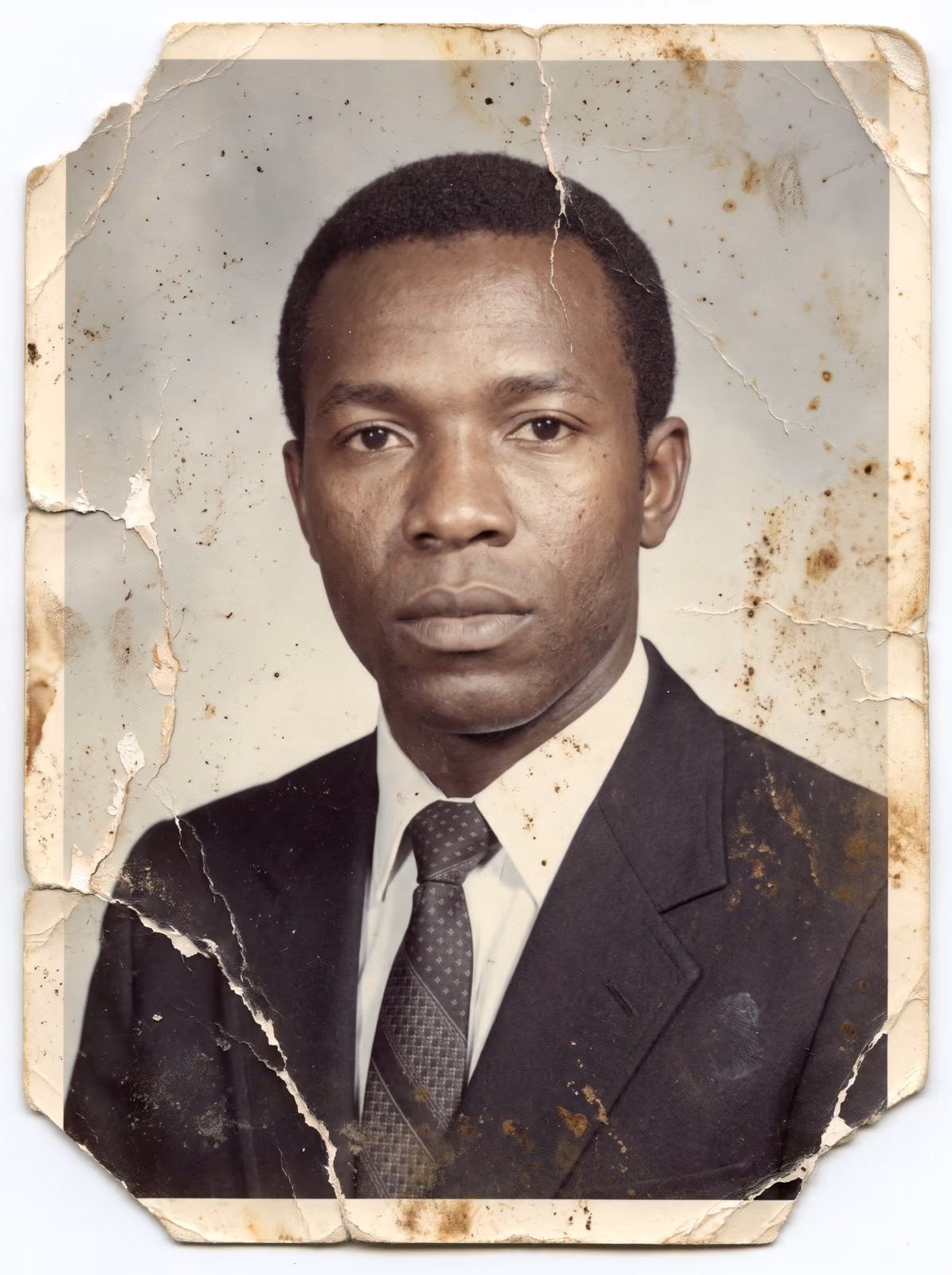 A creased colour portrait print of a man in a suit and tie before restoration