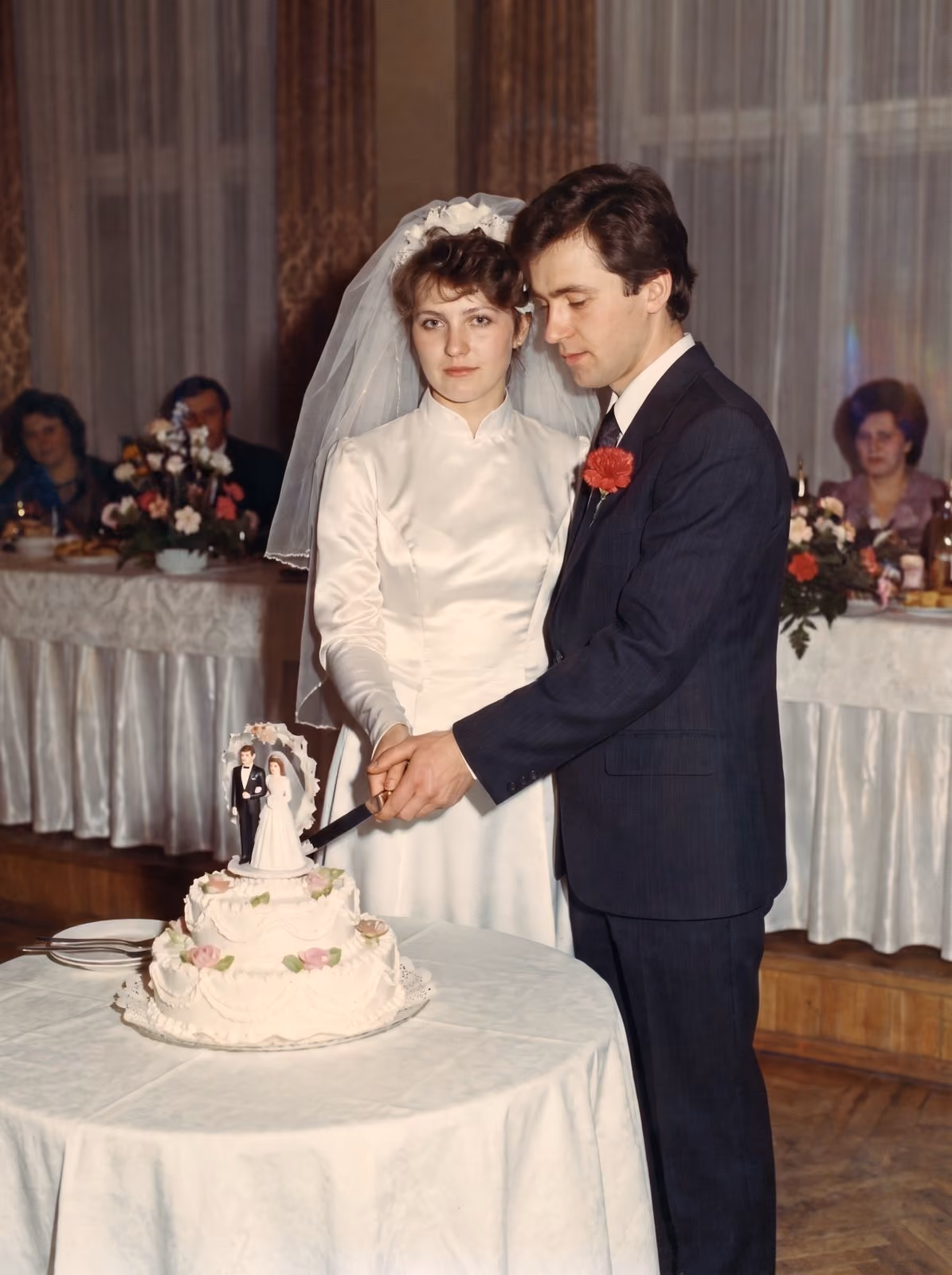 After: Newlyweds cutting a tiered wedding cake at the reception, restored from a cracked and stained print