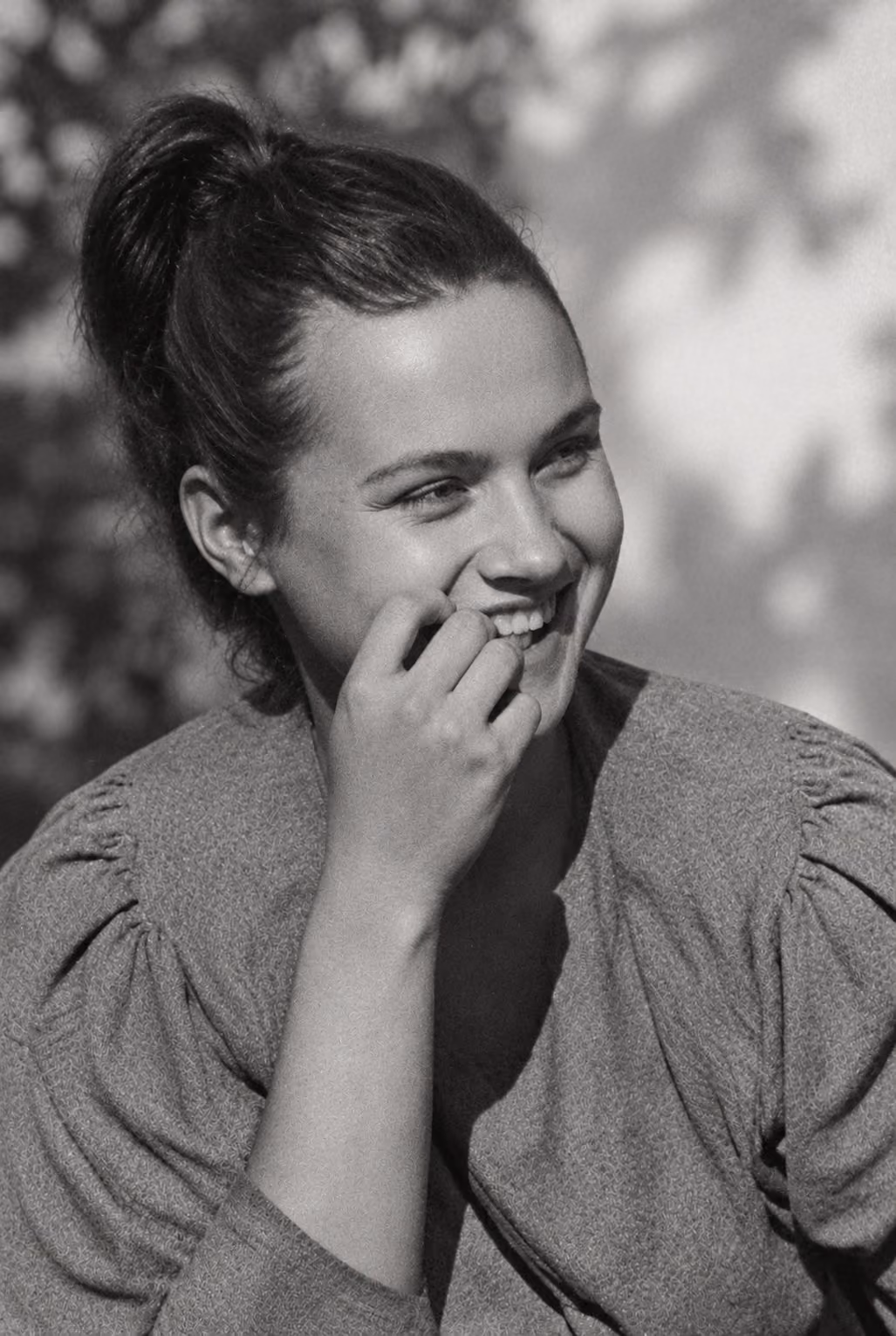 After: Candid portrait of a laughing woman with her hand at her chin, restored from a scratched print