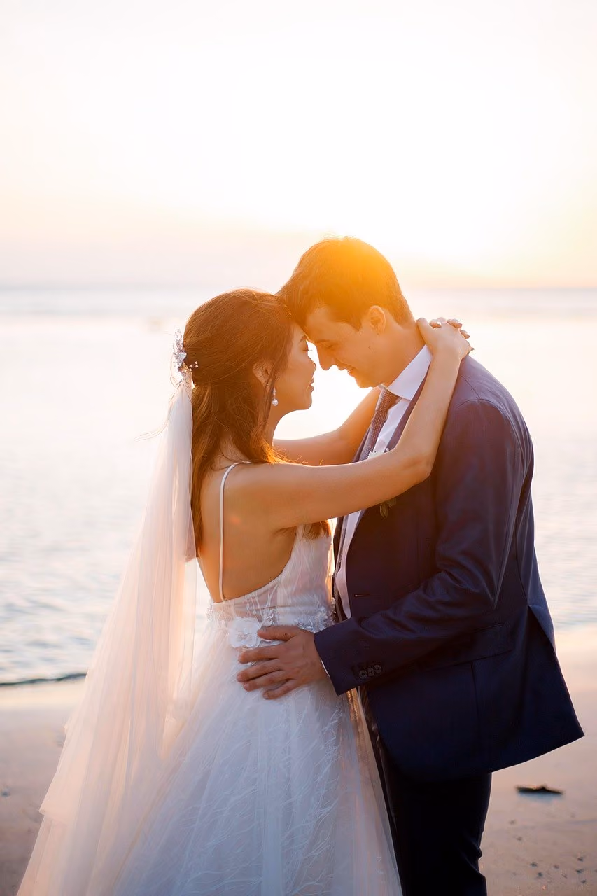After: Couple embracing on a beach at sunset, the bride in a long veil