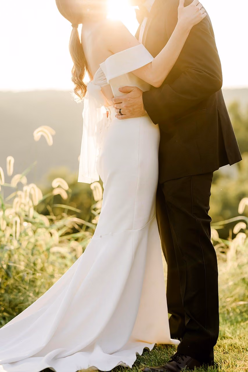 After: Bride and groom hugging in warm backlight on a hillside