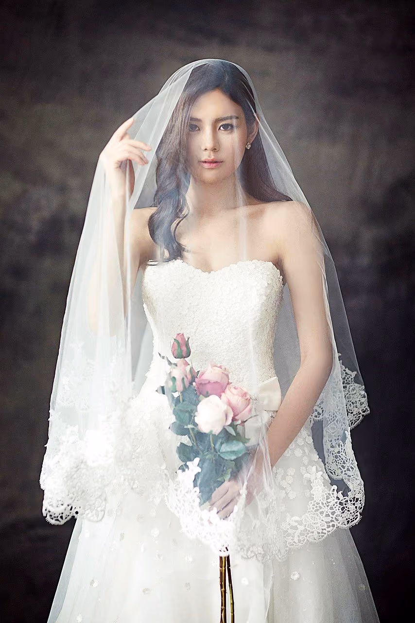 After: Bride in a lace veil holding a bouquet against a dark textured backdrop